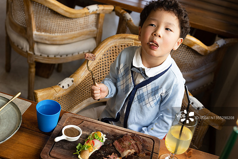 一个小男孩在餐厅吃牛排图片素材