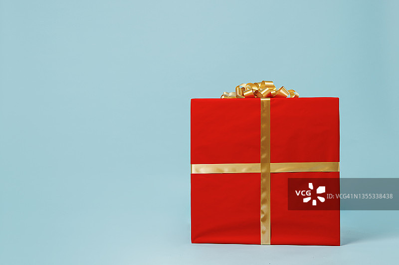 大大的大大的红色的圣诞礼物礼品盒，带着黄色的丝带，孤立在素色淡蓝色的背景画室肖像。2022年新年快乐庆典，圣诞快乐节日概念。图片素材