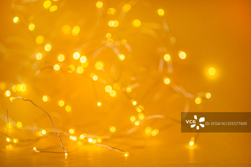 节日金色圣诞背景，由发光的散焦花环与许多灯。庆祝新年的概念。为您的设计复制空间图片素材