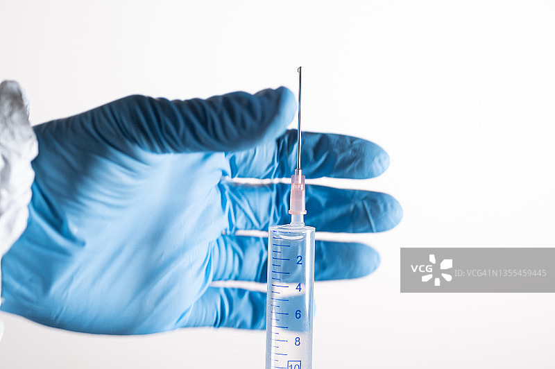 戴防护手套的人会被注射COVID-19疫苗的注射器所感染。背景是实验室样品。图片素材