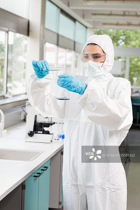 一幅受保护的女科学家向锥形烧瓶中倾倒液体的肖像图片素材