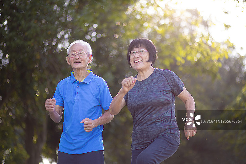 亚洲华人活跃的老年男子和妻子在早上一起在公园慢跑图片素材