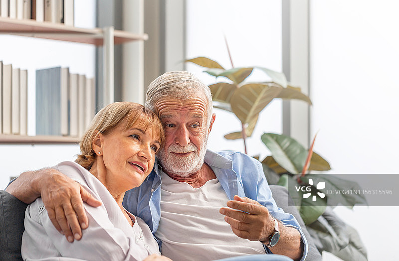 幸福的老夫妇在客厅里，老男人和老女人在家里舒适的沙发上放松，幸福的家庭观念图片素材