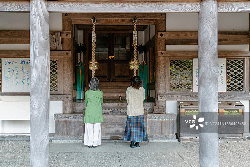 一位年长的妇女和她的成年女儿一起在寺庙祈祷图片素材