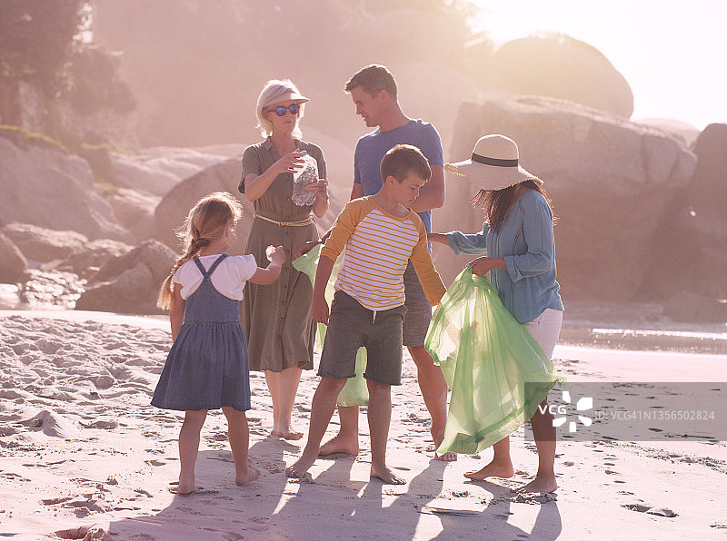 这是一个快乐的家庭为了拯救我们的星球而做海滩清理的完整镜头图片素材
