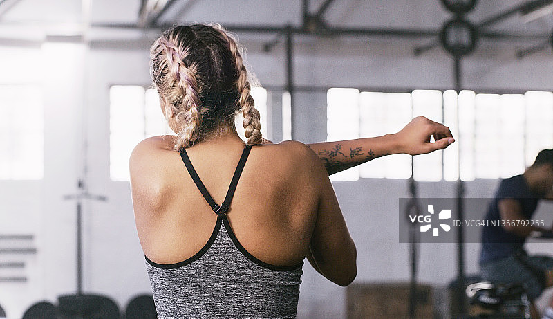 一个无法辨认的年轻健康女性在健身房锻炼前做热身伸展运动的后视镜图片素材