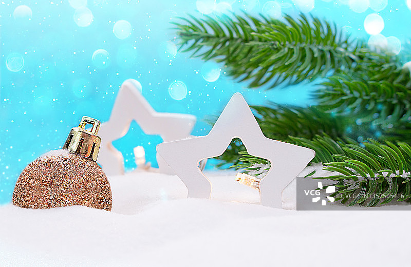 两个白色的星星灯笼和圣诞树玩具在雪地上用杉树的树枝。在蓝色背景上，雪花和散景。新的一年,冬天。本空间图片素材