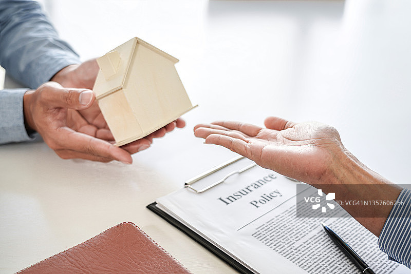 房地产销售经理在与客户签订房屋租赁合同或买卖协议后，将钥匙和房屋模型交给客户，涉及抵押贷款提供和房屋保险图片素材