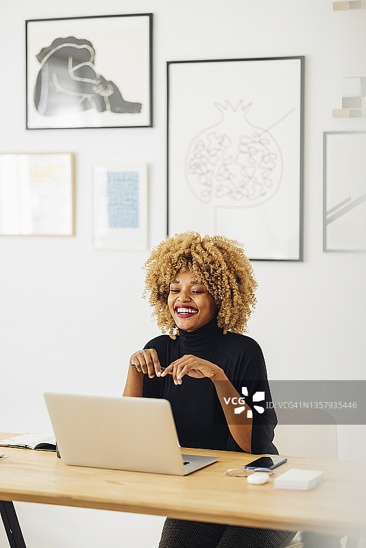 美丽的非裔美国妇女使用她的笔记本电脑，而在家工作图片素材
