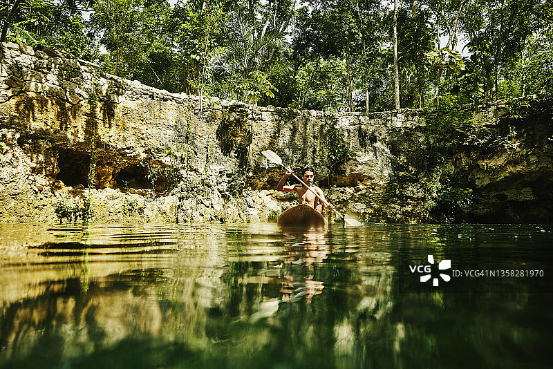 在丛林生态度假村的天然井里划皮划艇的男子宽镜头图片素材