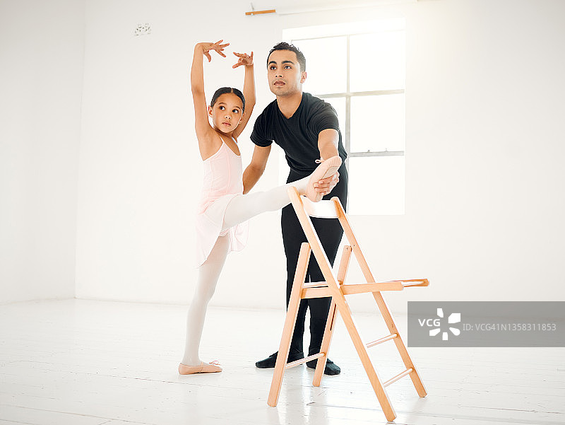 一名芭蕾舞老师在舞蹈工作室协助一名学生就位图片素材