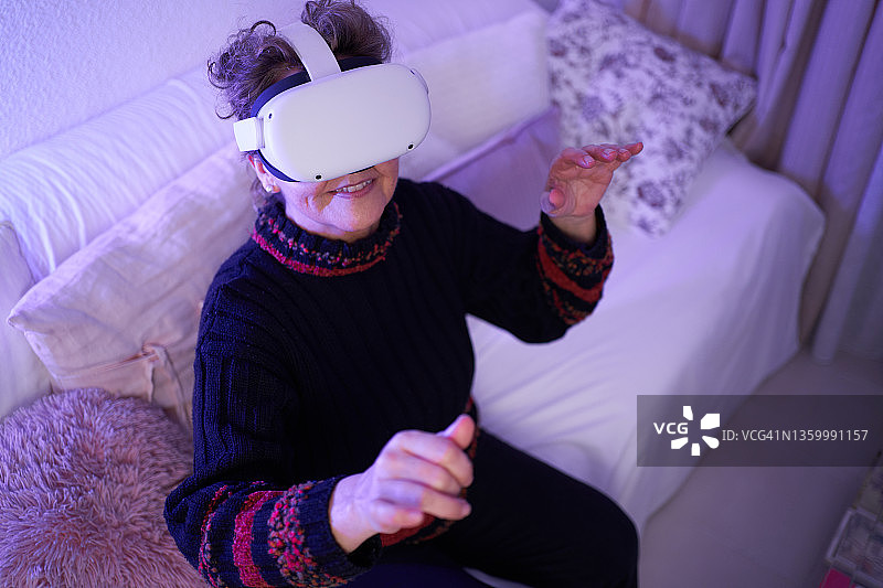 快乐的老妇人用VR耳机探索网络空间图片素材