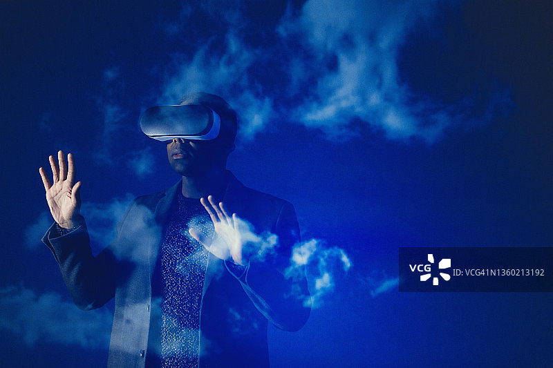 商人戴着虚拟现实模拟器眼镜，衬着蓝天白云图片素材