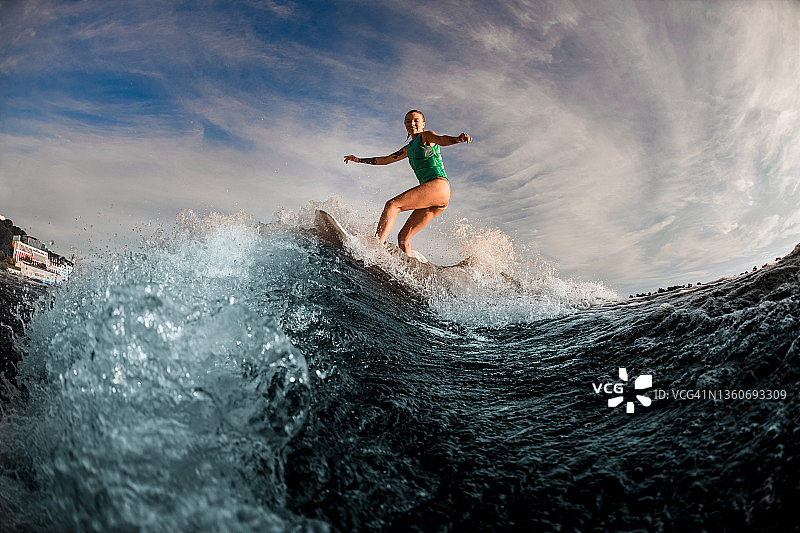 美丽的女子wakerfer骑在板上飞溅的波浪。图片素材
