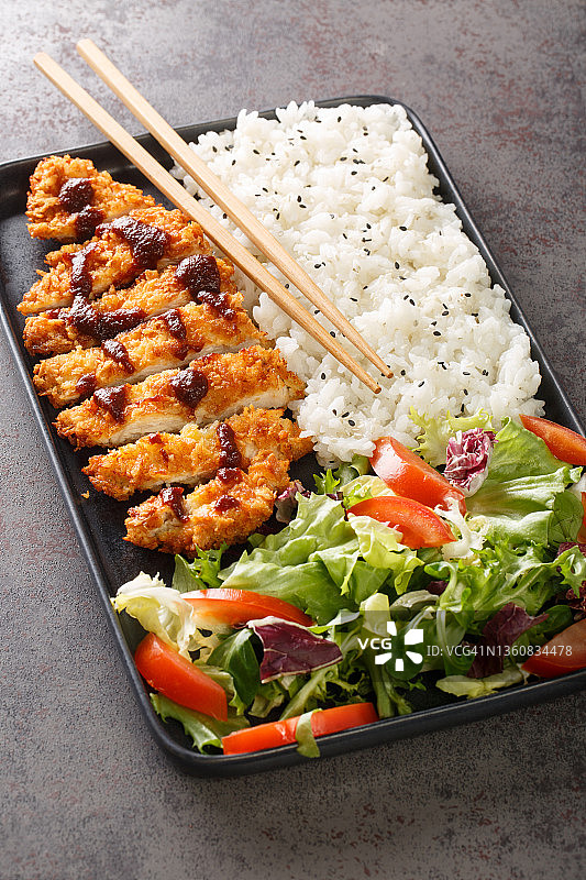 一盘猪排鸡配米饭和蔬菜沙拉的特写镜头。垂直图片素材
