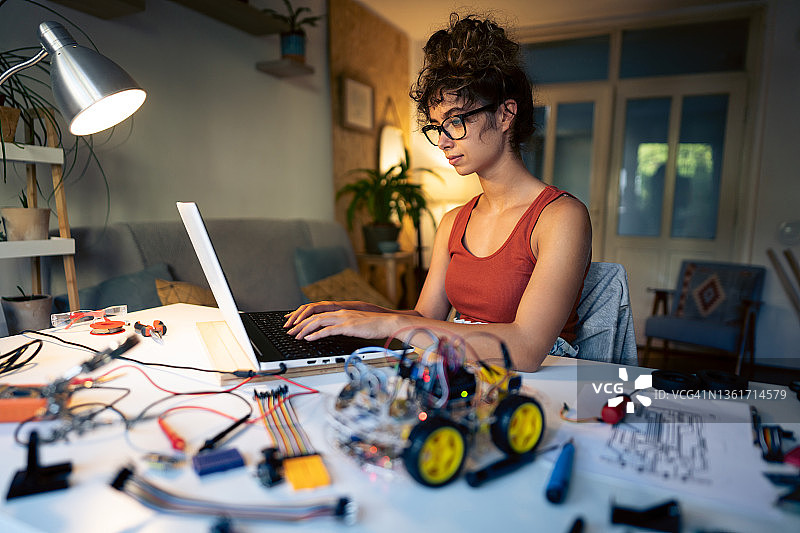 专注于女性程序员和机器人工程师，通过Arduino平台测试她的带有传感器的自动驾驶机器人汽车原型图片素材