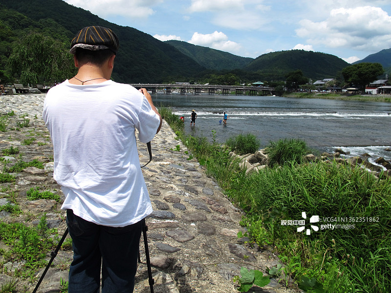 在日本关西京都市风景秀丽的大井河青山处，游客泰国男子旅游参观和拍摄拍摄照片观赏风景和日本父亲和儿子玩抓水族鱼图片素材
