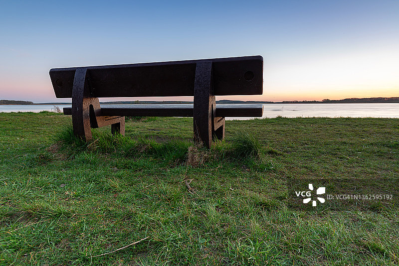 日落时坐在湖边的长椅上图片素材