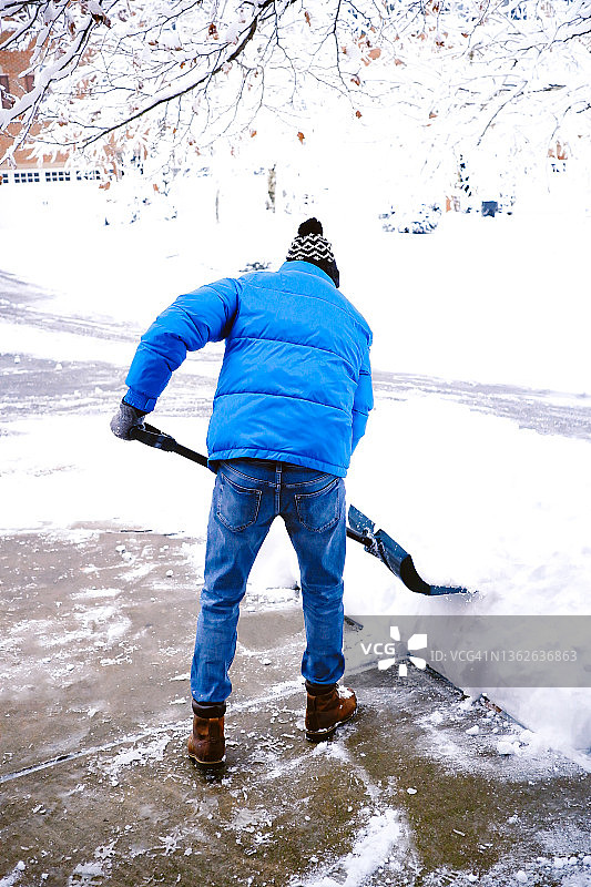 一名男子在暴风雪后从车道上铲雪图片素材