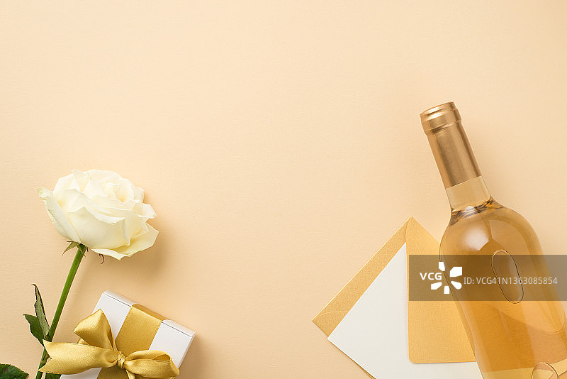 俯视图照片白玫瑰瓶白葡萄酒信封与卡和白色礼盒与金丝带蝴蝶结在孤立的米色背景与copyspace图片素材
