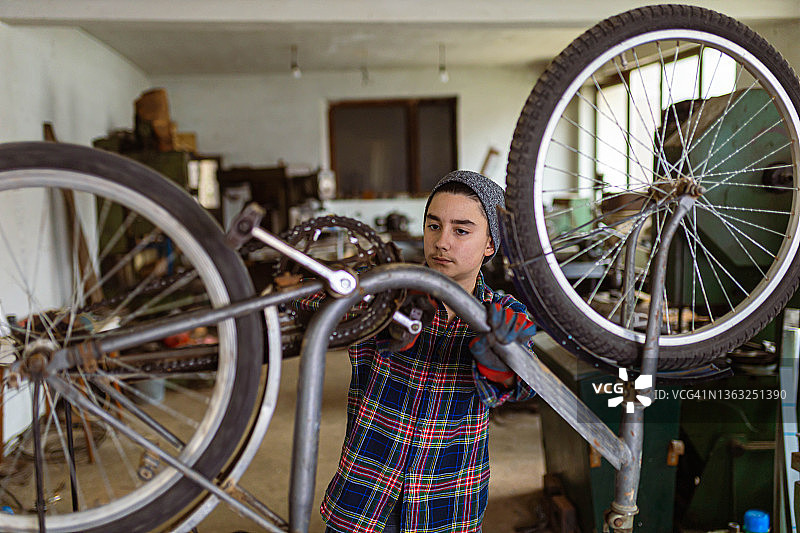 自学成才的十几岁男孩，在他的修车厂修理他的自行车图片素材