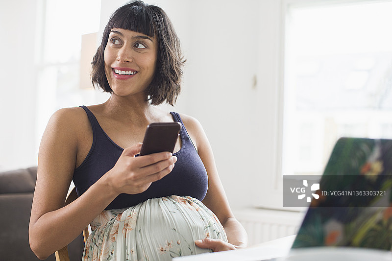 快乐的孕妇使用智能手机图片素材