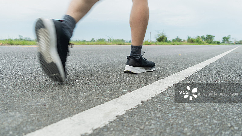 穿着黑色皮鞋的男运动员的腿正在准备在铺有路面的道路上奔跑。竞赛和成功的理念。图片素材
