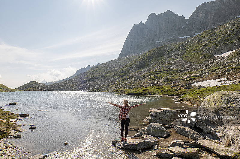 在瑞士美丽的高山湖附近，快乐的年轻女子张开双臂图片素材