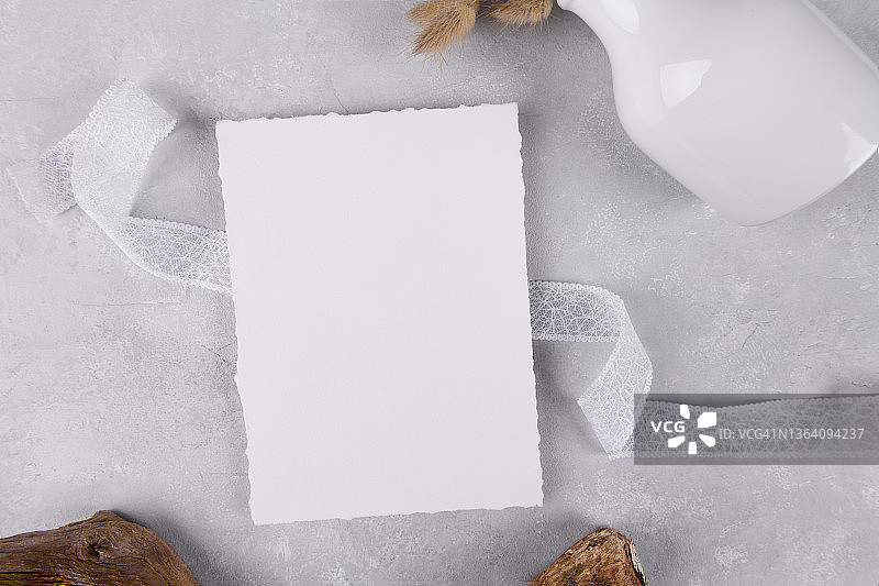 空白的婚礼邀请文具卡片模型在灰色石头桌子背景与白色丝带，5 × 7图片素材
