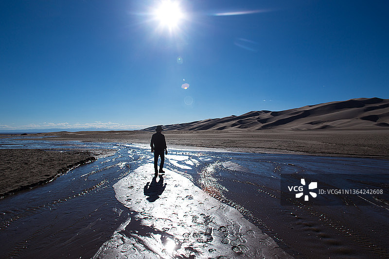 一名男子穿过科罗拉多大沙丘的溪流图片素材