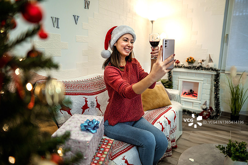 美丽的女人在圣诞节的时候一边喝酒一边打视频电话图片素材