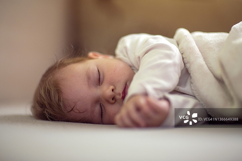 可爱的婴儿正在甜甜地睡觉。婴儿睡在柔软的白色毯子上图片素材