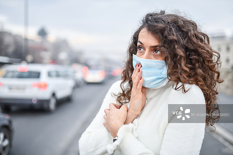 由于城市地区的污染，戴口罩的女性经历了非常糟糕的空气质量图片素材