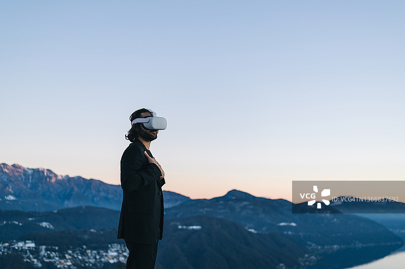 商人戴着VR眼镜在山脊上图片素材