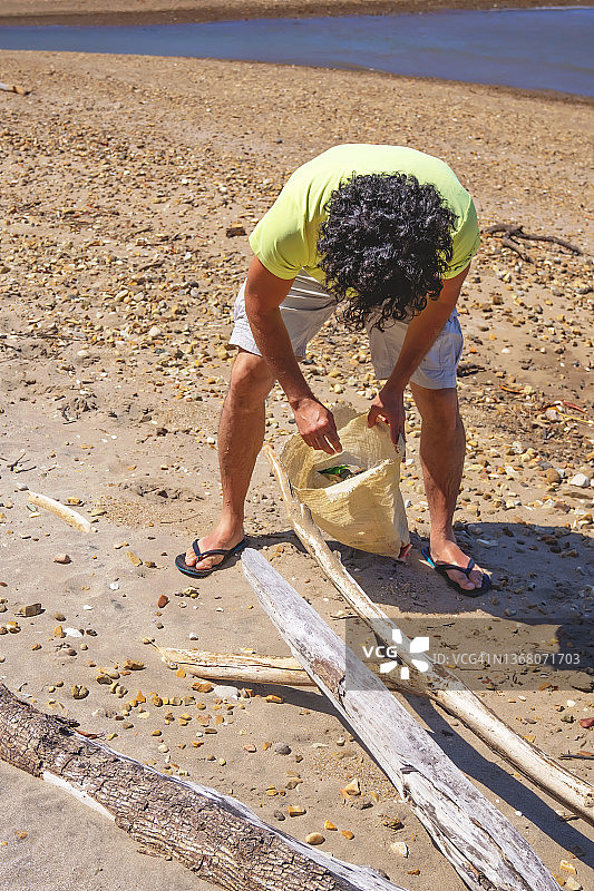 沙滩上的游客收集他在沙滩上发现的垃圾图片素材