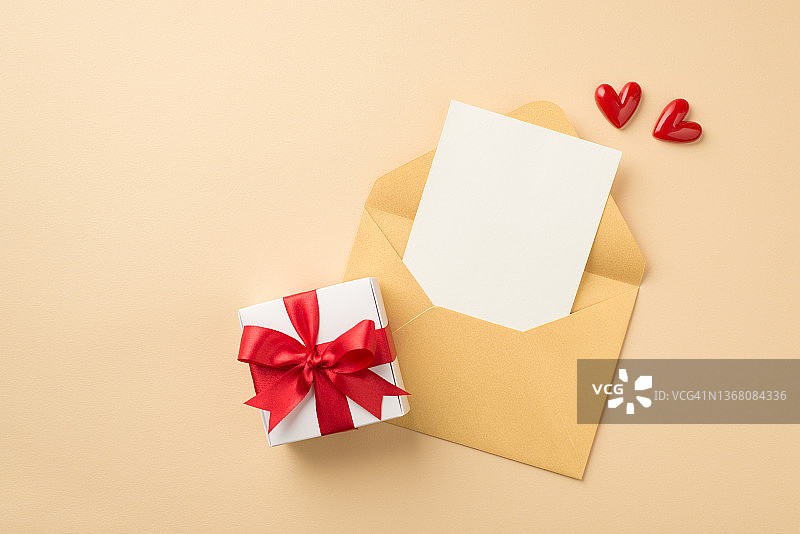 俯视图照片开放的蜡笔黄色信封与纸小红心和白色礼品盒红色丝带蝴蝶结在孤立的米色背景与空白空间图片素材