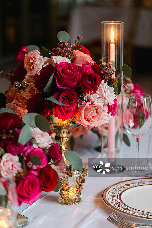 奢华的情人节婚礼接待细节与粉红色和红色的玫瑰花，蜡烛和华丽的桌子设置图片素材