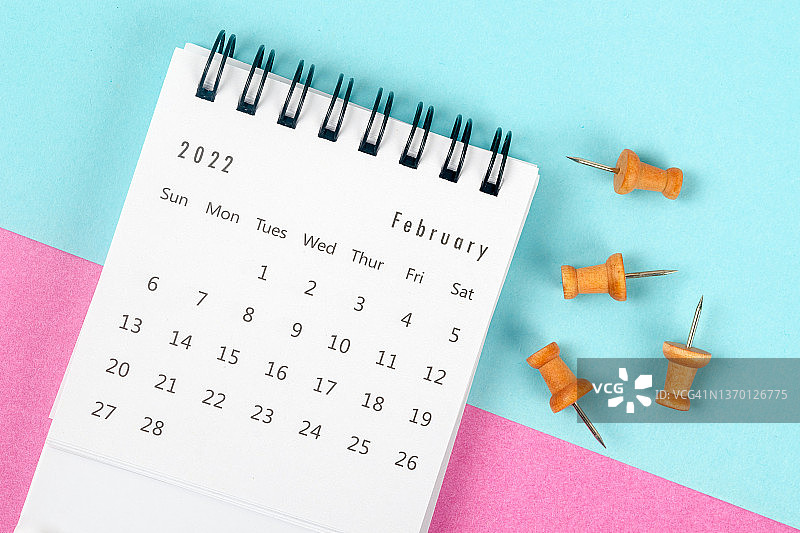 日历桌2022年2月是组织者计划和截止日期的月份，在双色纸背景上有一个图钉。图片素材