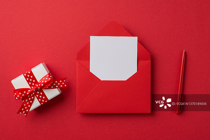 俯视图照片的情人节装饰打开红色信封与纸小白色礼品盒和笔在孤立的红色背景与空白空间图片素材