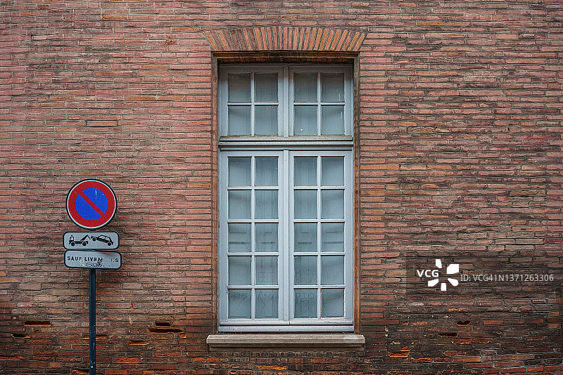 砖墙背景和玻璃窗，旁边有一个禁止停车的标志图片素材