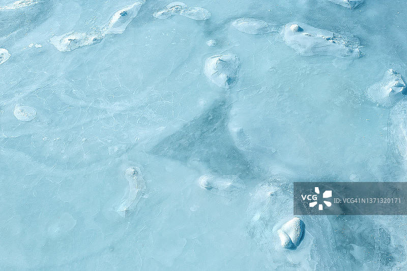 裂纹冰纹理的冬季冰冻冰表面蓝色背景。寒冷的冬霜河图片素材