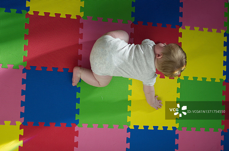 婴儿在彩色垫子上爬行图片素材