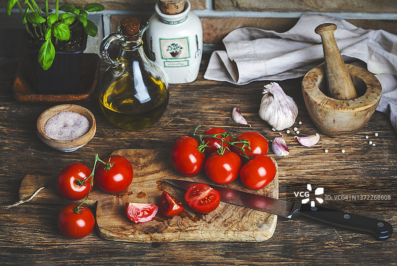 木桌上放着新鲜的番茄、大蒜和罗勒。乡村生活。素食。图片素材