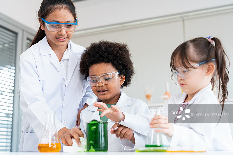 三个孩子在科学实验室里戴着防护眼镜图片素材