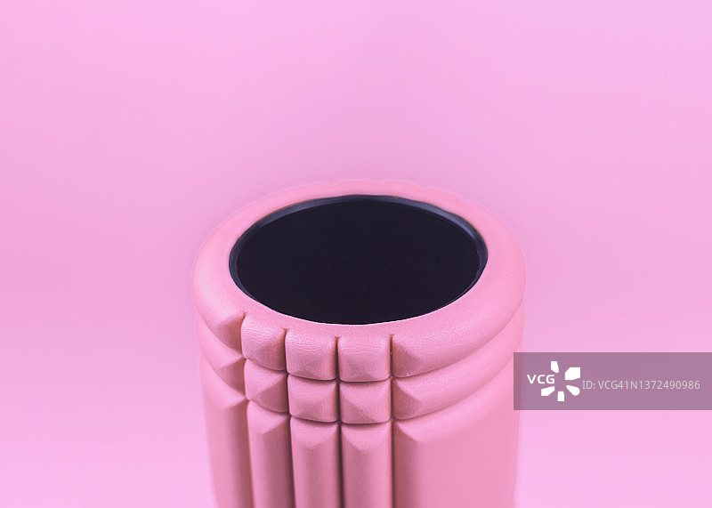 粉红色的泡沫辊在粉红色的背景。图片素材