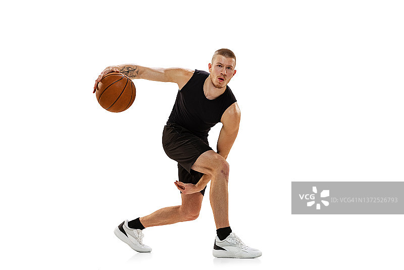 年轻的肌肉男，篮球运动员，在白色的工作室背景下练习篮球。运动，运动，活动的概念。图片素材
