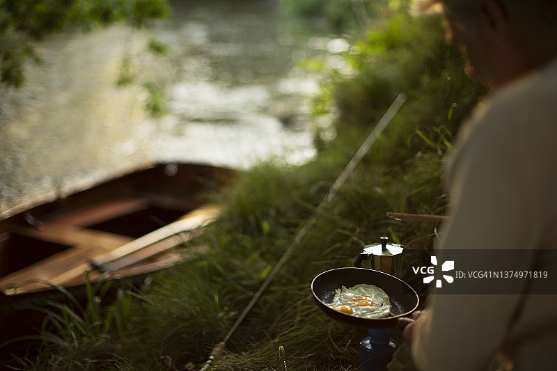 一名男子在河边的鱼竿上孵蛋图片素材