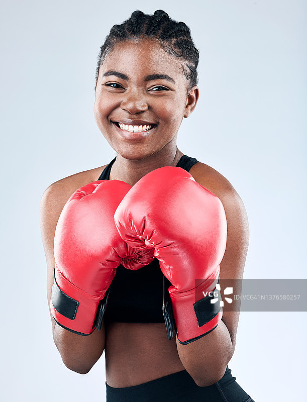 摄影棚拍摄的一个运动的年轻女子戴着拳击手套，在摄影棚的背景下摆姿势图片素材