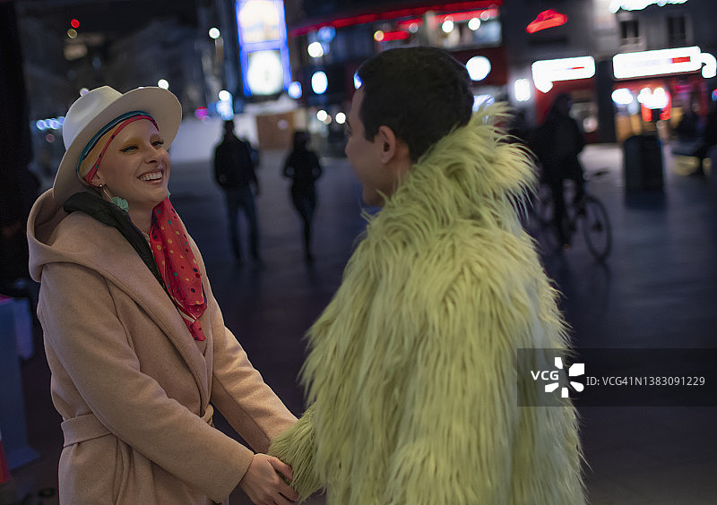 幸福时尚的夫妇手牵手在城市的街道在晚上图片素材