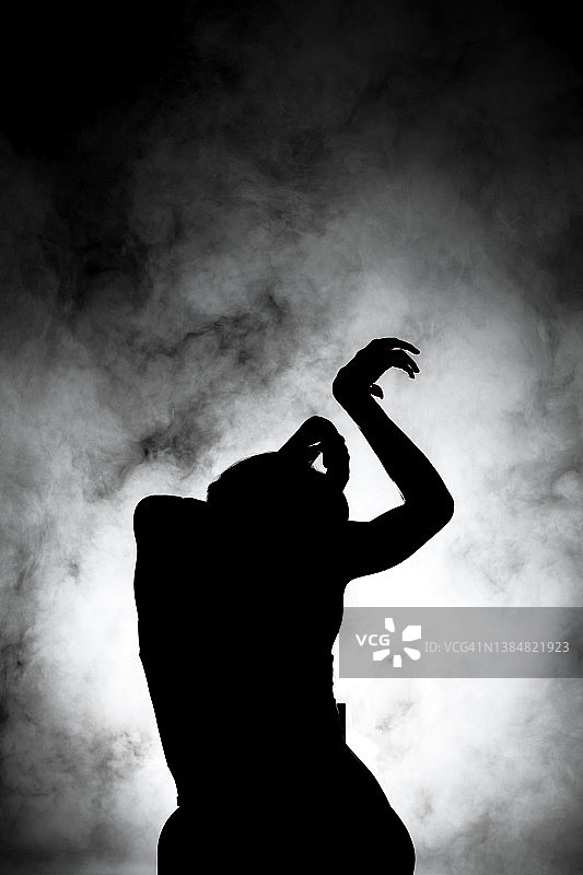 剪影现代芭蕾舞演员摆姿势在黑暗的背景与烟图片素材